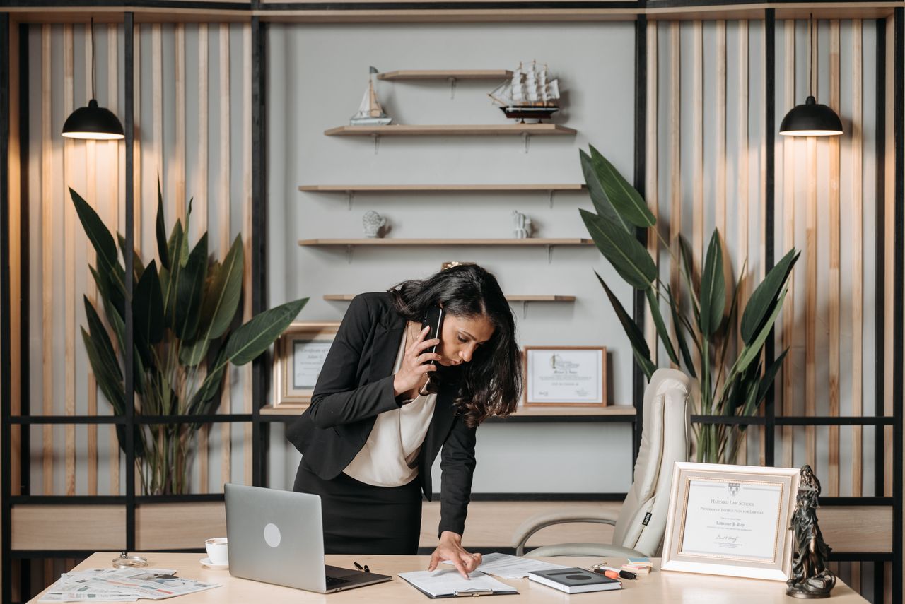 Mastering the First Impression: Your intriguing post title goes here A professional woman lawyer multitasking in a modern office environment, reviewing documents.